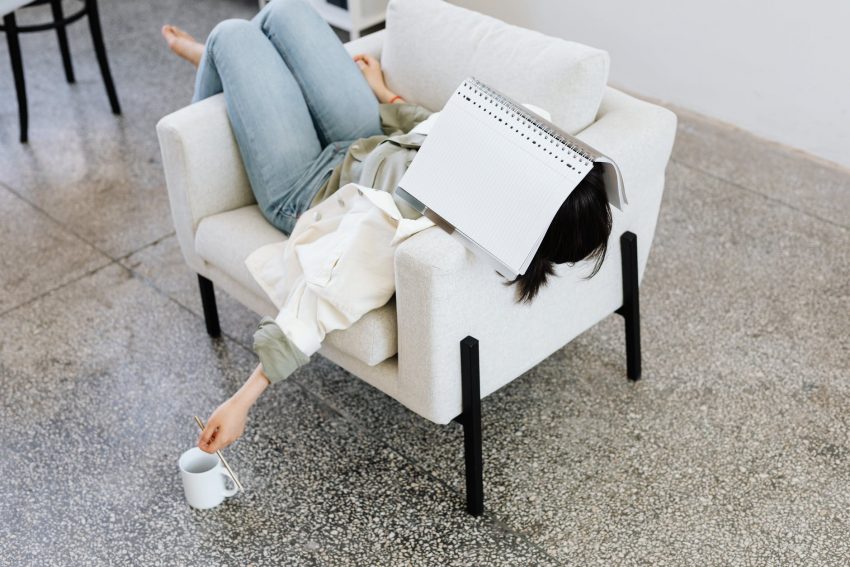 woman in long sleeves and denim pants lying on a couch